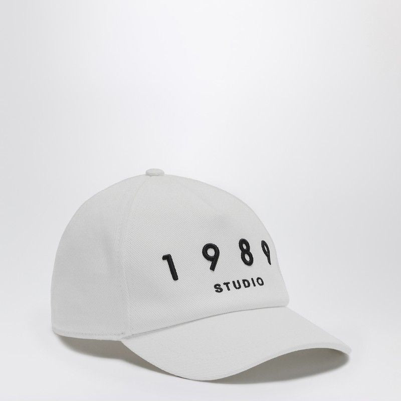 White baseball cap with black 1989 Studio embroidery, fashion accessory on plain background