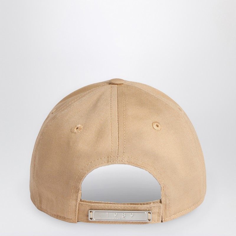 Beige cotton baseball cap with adjustable metal clasp and embroidered ventilation eyelets.